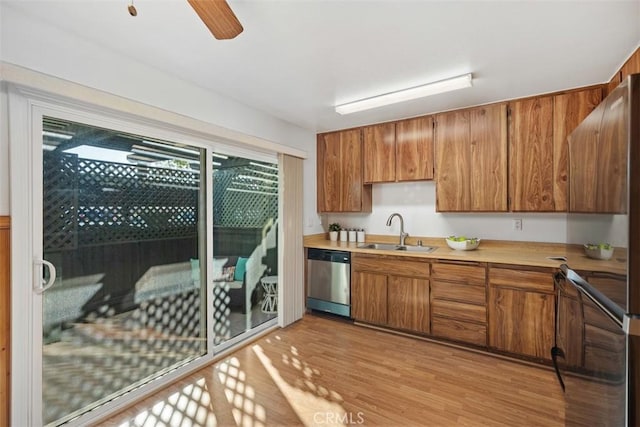 kitchen with dishwasher, light wood finished floors, a sink, and brown cabinets