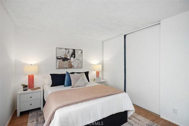 bedroom featuring a closet, a textured ceiling, and wood finished floors