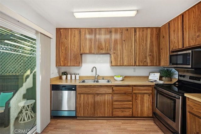 kitchen featuring appliances with stainless steel finishes, brown cabinetry, and a sink