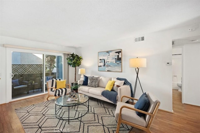 living room with baseboards, visible vents, and wood finished floors