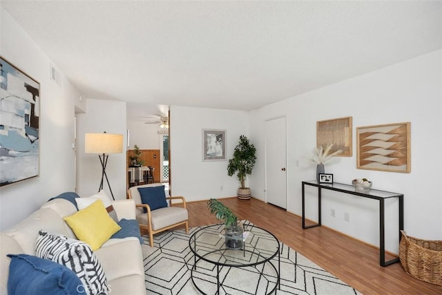 living room with ceiling fan, visible vents, and wood finished floors