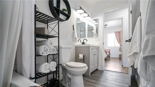 bathroom featuring toilet, wood finished floors, vanity, and baseboards