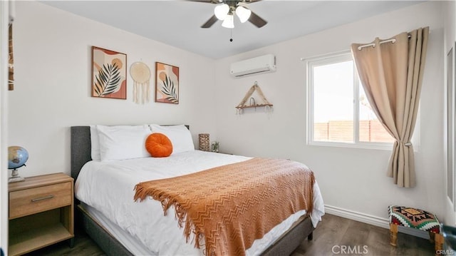 bedroom with ceiling fan, baseboards, an AC wall unit, and wood finished floors