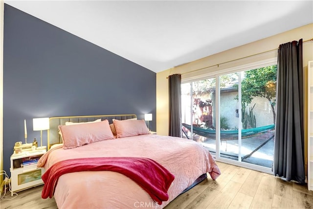 bedroom featuring lofted ceiling, wood finished floors, and access to exterior