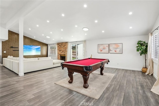 playroom with lofted ceiling, a stone fireplace, recessed lighting, wood finished floors, and baseboards