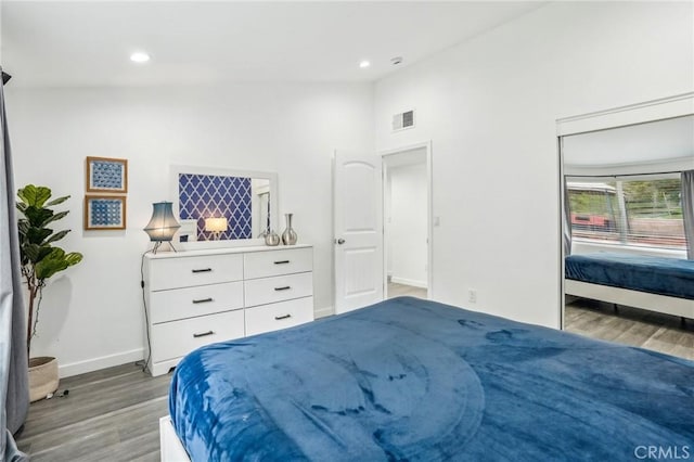 bedroom with lofted ceiling, recessed lighting, wood finished floors, visible vents, and baseboards