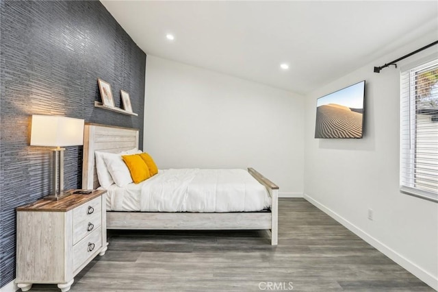 bedroom featuring an accent wall, baseboards, wood finished floors, and recessed lighting