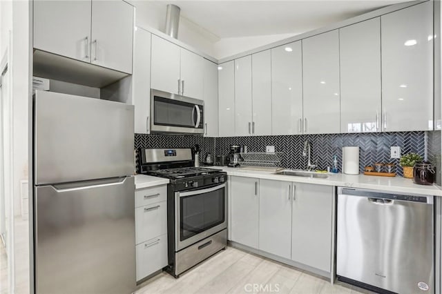 kitchen featuring light countertops, appliances with stainless steel finishes, backsplash, and a sink