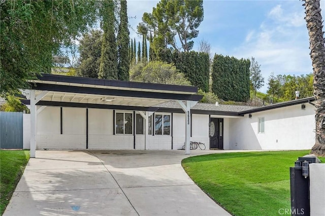 view of front of house with stucco siding, concrete driveway, a front yard, fence, and a carport