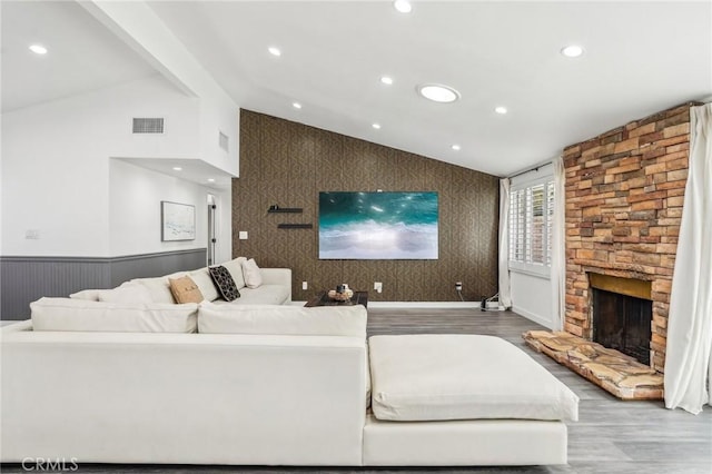 living room featuring lofted ceiling, a fireplace, recessed lighting, and wood finished floors