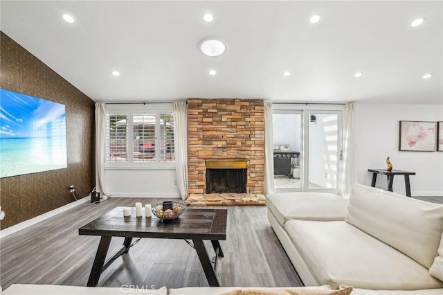 living area featuring a fireplace, an accent wall, wood finished floors, and recessed lighting