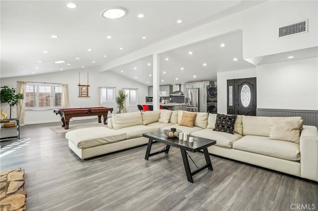 living area featuring stacked washer and dryer, pool table, visible vents, lofted ceiling with beams, and wood finished floors