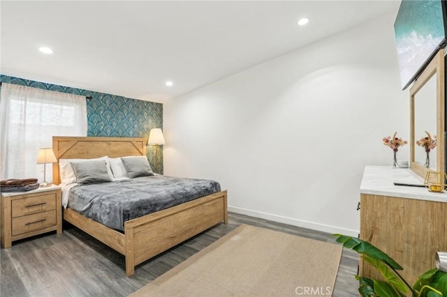 bedroom with an accent wall, baseboards, wood finished floors, and recessed lighting