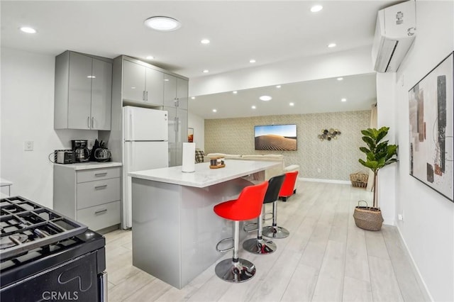 kitchen with wallpapered walls, freestanding refrigerator, a wall mounted air conditioner, gray cabinetry, and recessed lighting