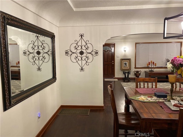 dining room featuring baseboards, arched walkways, and wood finished floors