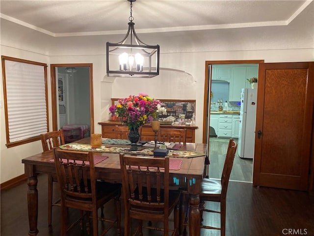 dining area with a chandelier, dark wood-style flooring, and baseboards