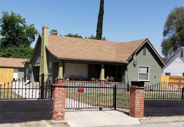 view of front of property with roof with shingles, a fenced front yard, a gate, and stucco siding