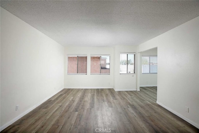 unfurnished room featuring dark wood finished floors, a textured ceiling, and baseboards