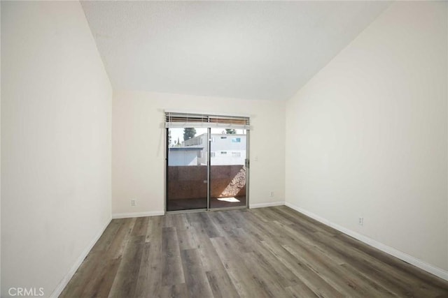 empty room with vaulted ceiling, baseboards, and wood finished floors