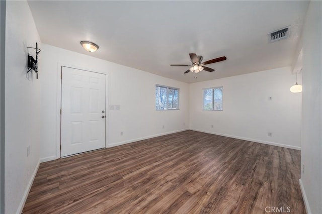 unfurnished room with dark wood-type flooring, visible vents, baseboards, and ceiling fan