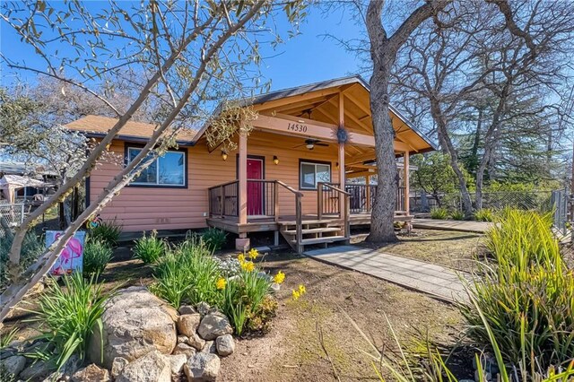 view of front of property with a ceiling fan and fence