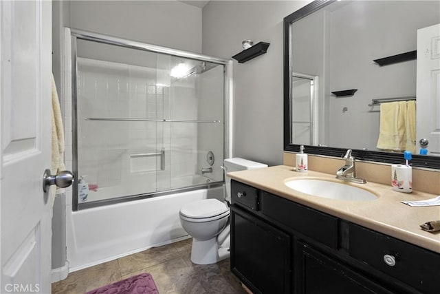 bathroom with vanity, toilet, and bath / shower combo with glass door