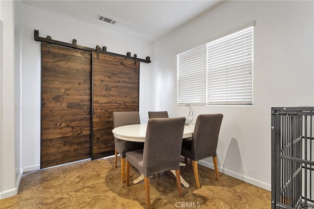 dining room featuring a barn door, visible vents, and baseboards