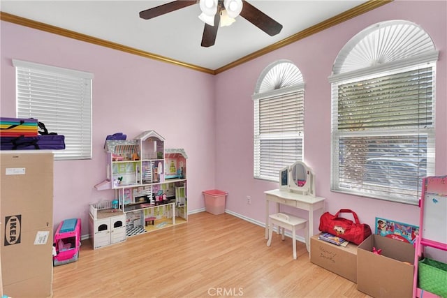 game room featuring a ceiling fan, baseboards, crown molding, and wood finished floors