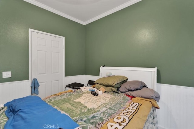 bedroom featuring a wainscoted wall and crown molding