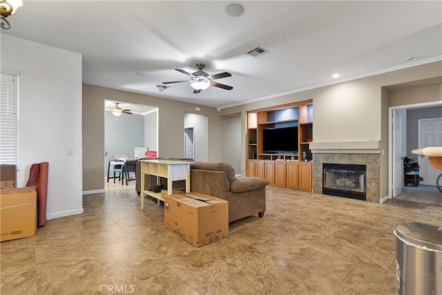 living room featuring a fireplace, visible vents, a ceiling fan, ornamental molding, and baseboards