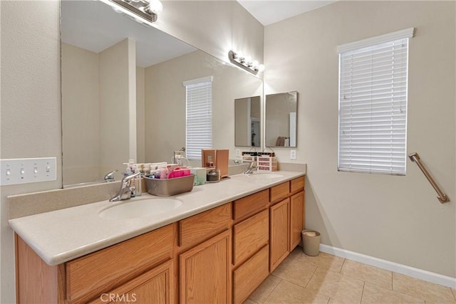 full bath with double vanity, tile patterned flooring, baseboards, and a sink