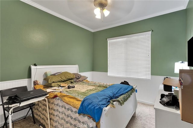 bedroom with ornamental molding, carpet, wainscoting, and ceiling fan