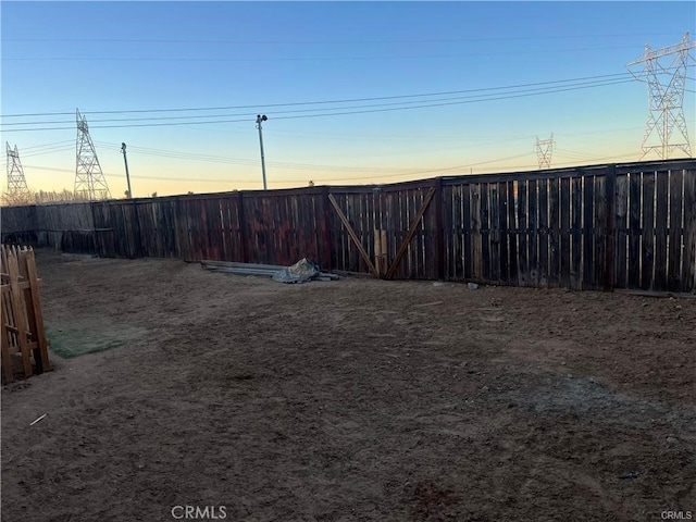 yard at dusk with a fenced backyard