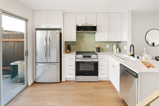 kitchen with stainless steel appliances, light countertops, a sink, and light wood finished floors