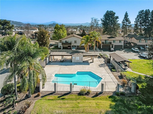 pool with a residential view, a mountain view, fence, and a patio