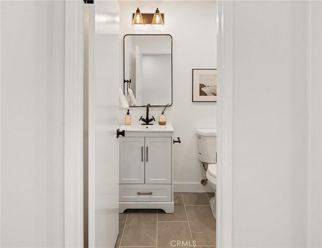 half bath with baseboards, vanity, toilet, and tile patterned floors