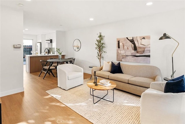 living room featuring recessed lighting, light wood-style flooring, and baseboards