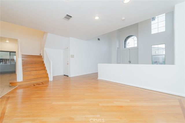 empty room featuring light wood-type flooring, visible vents, stairway, and recessed lighting