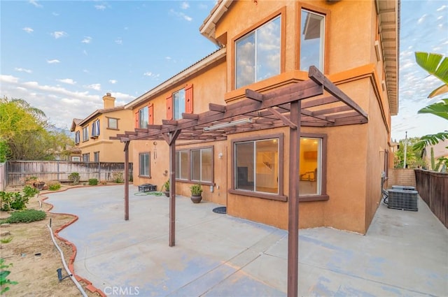 back of house featuring a patio area, a fenced backyard, a pergola, and stucco siding