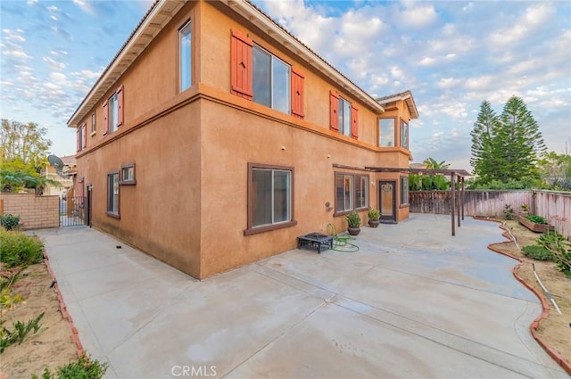 exterior space featuring a patio, fence private yard, a gate, and stucco siding