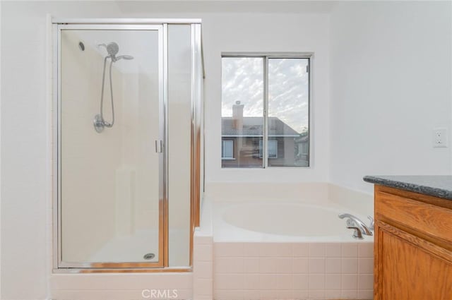 full bath with a shower stall, vanity, and a bath