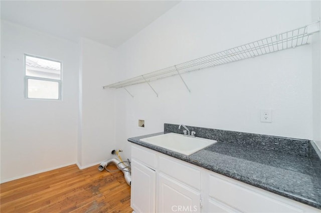 clothes washing area with light wood-type flooring, washer hookup, a sink, and baseboards