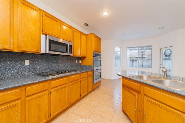 kitchen with tasteful backsplash, visible vents, stainless steel appliances, a sink, and light tile patterned flooring