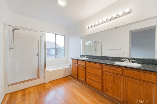 full bath featuring a garden tub, wood finished floors, a sink, a shower stall, and double vanity