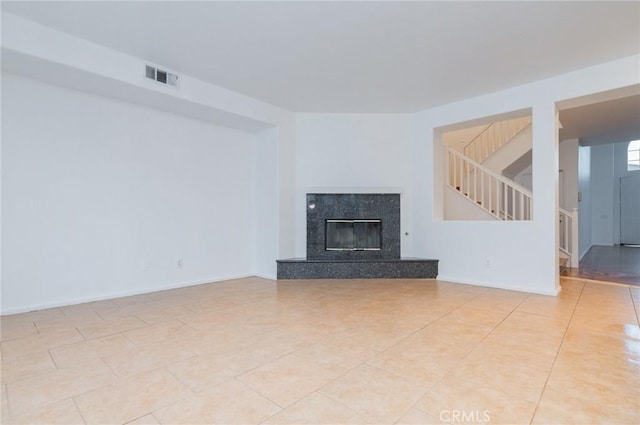 unfurnished living room featuring visible vents, baseboards, stairs, a fireplace, and light tile patterned flooring