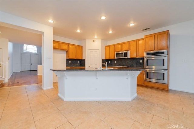 kitchen featuring tasteful backsplash, visible vents, brown cabinets, stainless steel appliances, and light tile patterned flooring