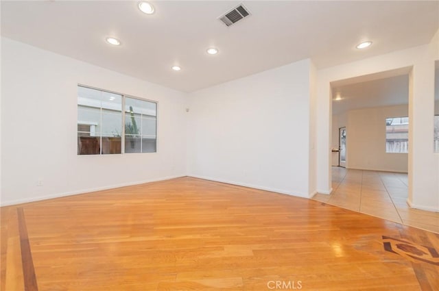 empty room with light wood-style flooring, visible vents, baseboards, and recessed lighting