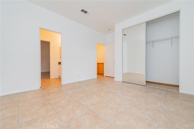 unfurnished bedroom featuring light tile patterned floors, a closet, and visible vents