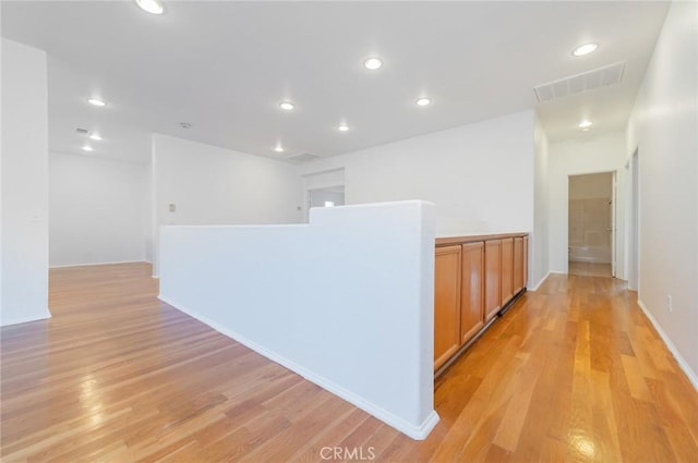 hallway with light wood-type flooring, baseboards, visible vents, and recessed lighting