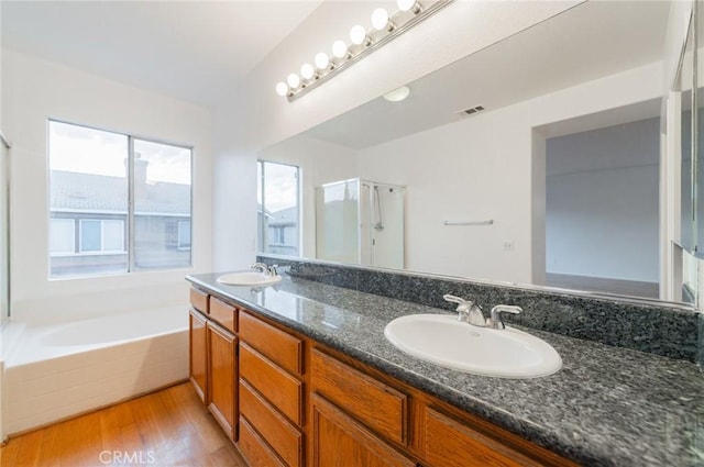 full bathroom featuring a stall shower, a garden tub, a sink, and wood finished floors